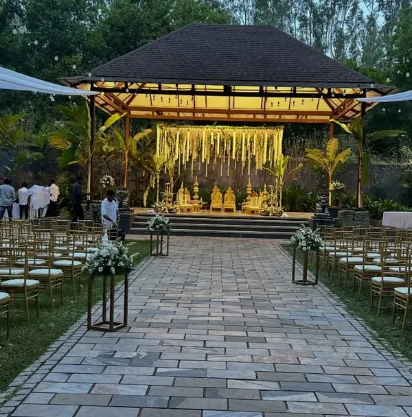 This wide-angle view shows a complete outdoor wedding setup at a resort. We arranged the guest seating along a stone pathway leading to the beautifully lit mandap, with white drapes overhead to create an elegant, open-air wedding venue.