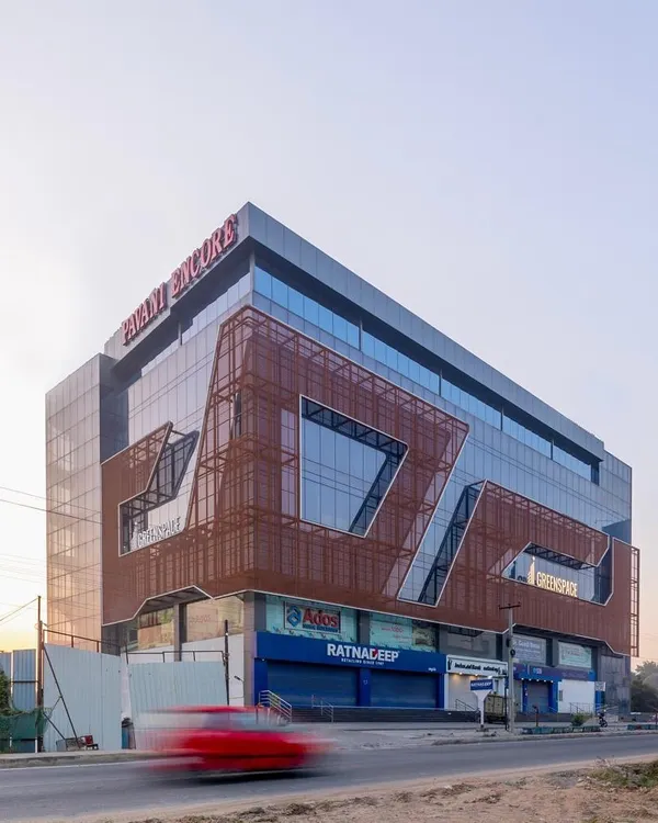 The facade of this commercial building is fluidic and minimalistic, using glass and expanded metal as primary materials. This lends a futuristic touch to the built form, which houses retail on the ground floor and offices above.