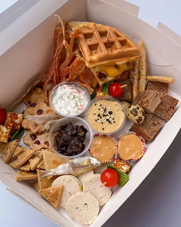 This is my 'Bobo's Grazing Board', the ultimate Diwali indulgence for your dog. It's a huge assortment of savory and sweet treats, including chicken jerky, anchovies, paneer skewers, brownies, and even a waffle burger.