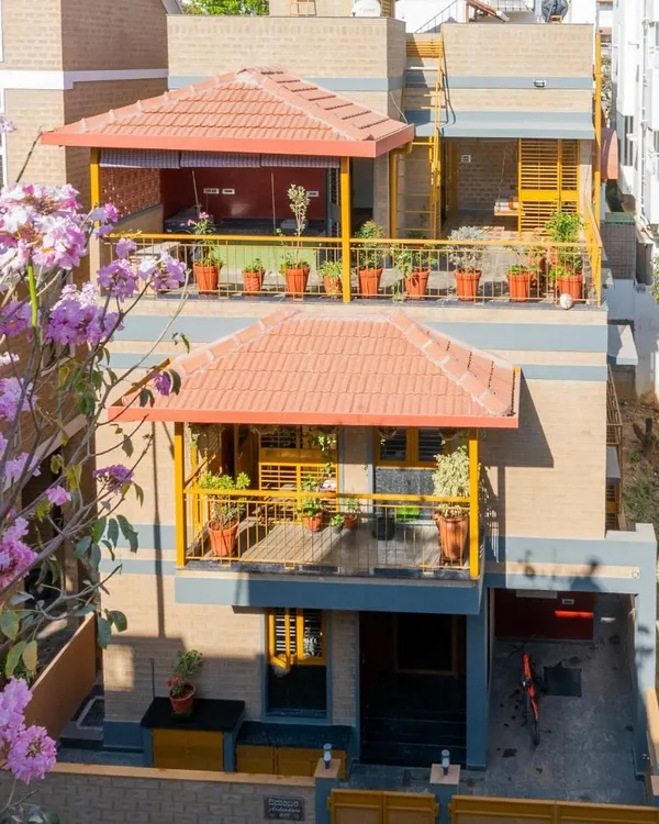 This is my Audumbara project, a home built with Compressed Stabilised Earth Blocks (CSEB). The design embraces the Bangalore climate, with deep balconies and Mangalore tile roofs that provide shade and character, all framed by the natural beauty of the surroundings.