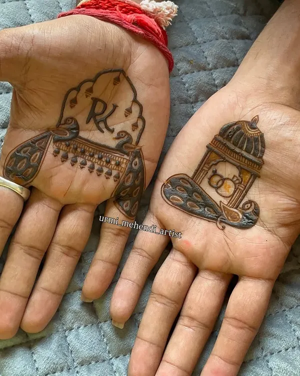 A classic groom's mehendi design. One hand features the couple's initials 'R' and 'K' inside a peacock motif, while the other has a doli (palanquin) with wedding rings, symbolizing the journey ahead.
