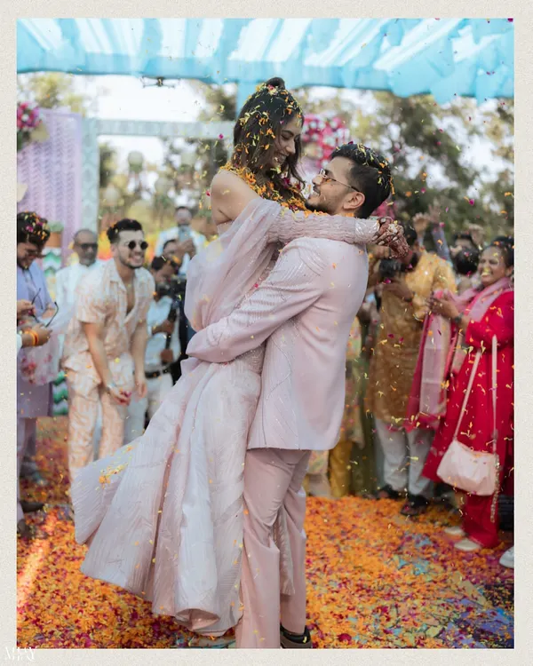 A moment of pure fun as the groom lifts the bride amidst a shower of flower petals during their Haldi carnival.
