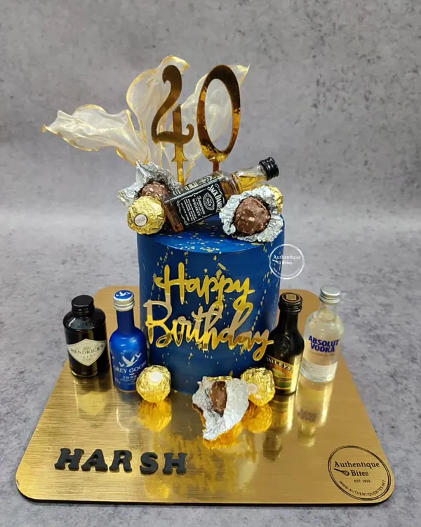 A loaded liquor and chocolate cake for a 40th birthday. This non-fondant blue and gold cake is topped with miniature alcohol bottles and Ferrero Rocher chocolates.