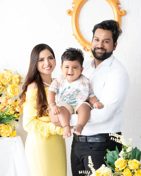 A bright and happy family portrait with a cheerful yellow theme. The family of three shares a beautiful smile, capturing a moment of pure joy in a studio decorated with yellow flowers.