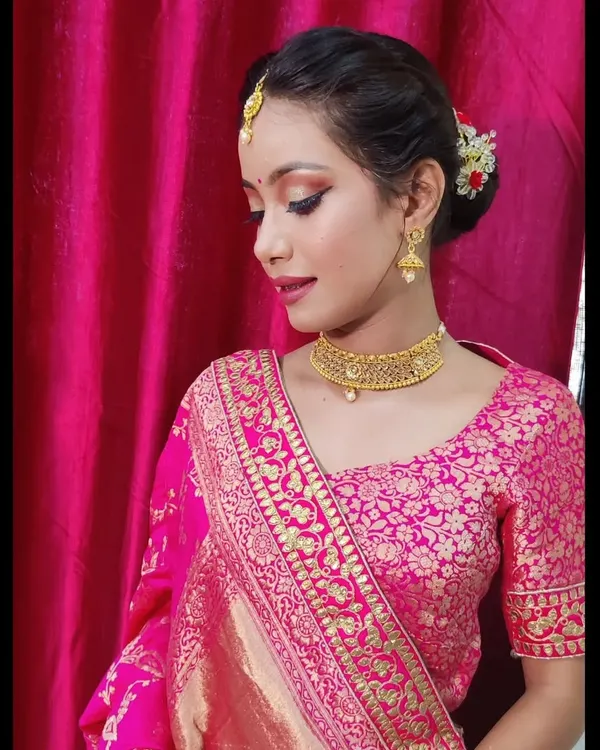 A detailed view of this festive makeup, highlighting the sharp winged eyeliner and delicate gold jewelry. The hair is neatly tied in a traditional bun with flowers, a timeless choice for any ethnic celebration.