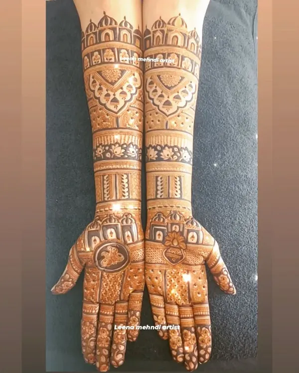 This full-arm bridal mehndi features architectural domes and intricate jaali (lattice) work. The design is symmetrical and packed with detail, perfect for a bride wanting a traditional and grand look.