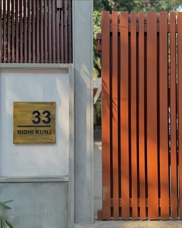 The entrance to '33 Nidhi Kunj', a soulful renovation project in New Delhi. The clean lines of the gate and the simple, elegant nameplate signal the modern and minimalist design language of the home within.