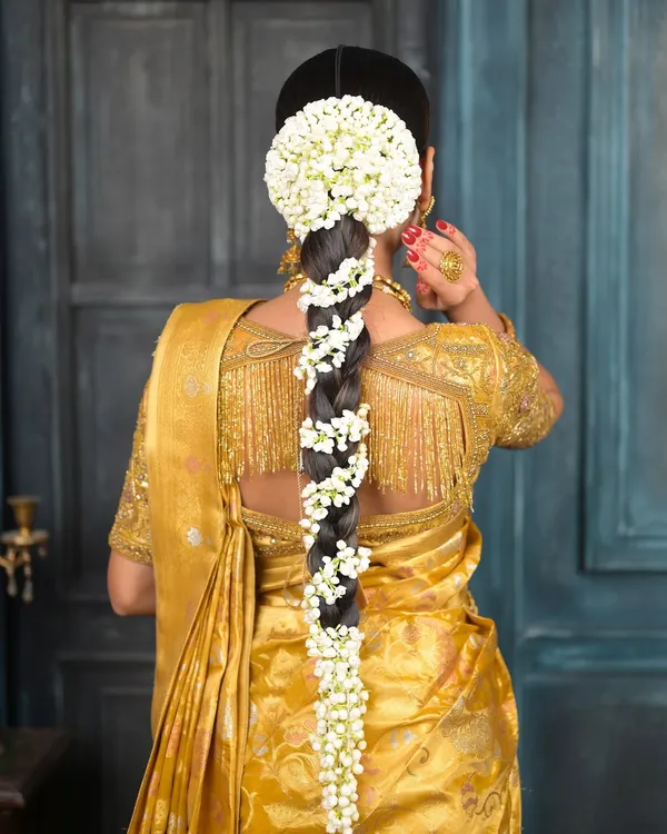 The quintessential South Indian bridal hairstyle. A long, thick braid beautifully adorned with fresh jasmine flowers (gajra), paired with a traditional bun at the top.