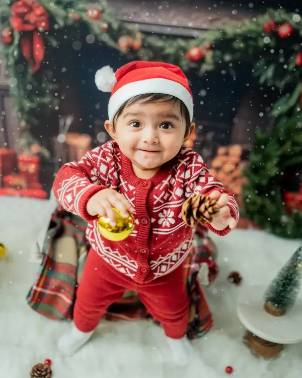 A toddler's first Christmas! This little one is having fun exploring the festive props like pinecones and shiny ornaments in my cozy, fireplace-themed holiday set.