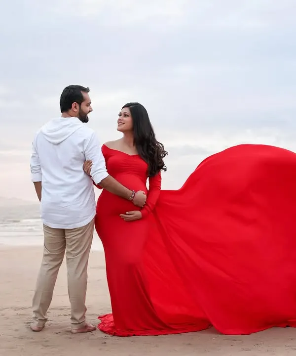 A breathtaking moment on the beach. The vibrant red of her flowing gown against the soft colors of the sea and sky creates a powerful and unforgettable image.