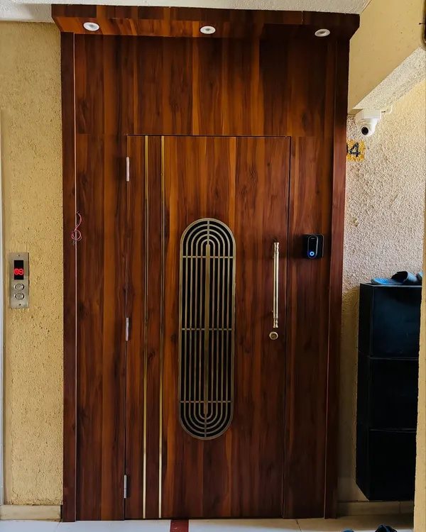 I designed this grand entrance with a solid wood safety door featuring a metal grill and brass inlays. The entire entrance area is panelled in wood to create an impressive and welcoming entryway.