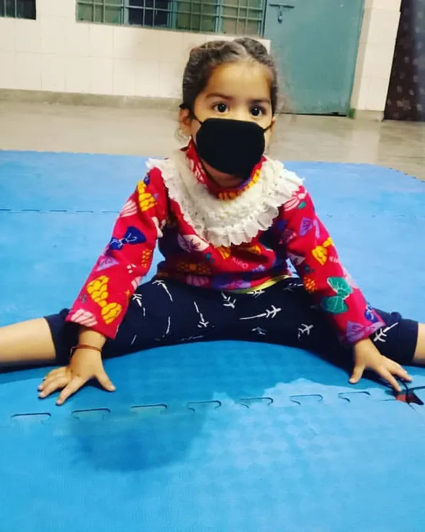 We start building a strong foundation early. This young girl is working on her flexibility, an essential part of our karate for kids program that helps prevent injuries and improves technique.