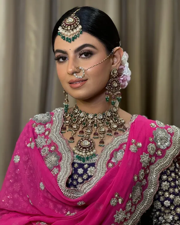 A stunning Sikh bride ready for her Anand Karaj. I created a sleek, low bun adorned with fresh flowers to securely hold her dupatta while complementing her intricate jewellery, including the maang tikka and passa.