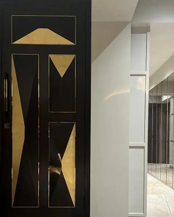 The entrance to this Juhu apartment features a custom-designed door with striking geometric brass inlays. This bespoke detail serves as a piece of art and sets a luxurious tone from the very first step inside.