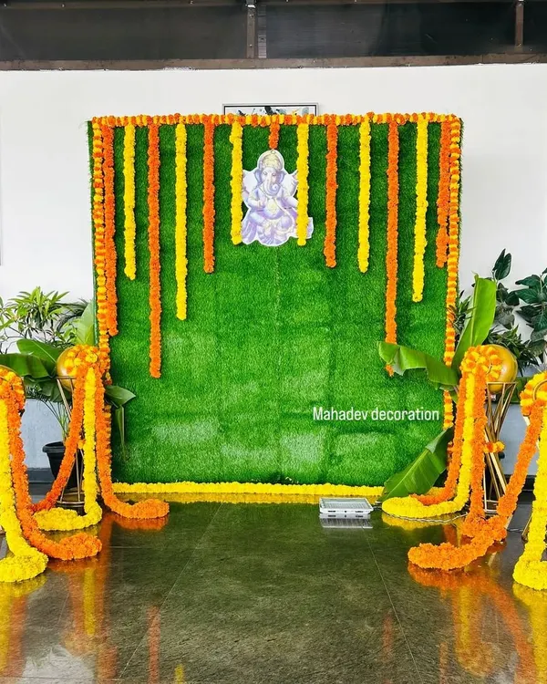 For a traditional ceremony or pooja, I created this backdrop using an artificial green grass wall. It is decorated with vertical garlands of fresh marigold flowers and a central picture of Lord Ganesha.