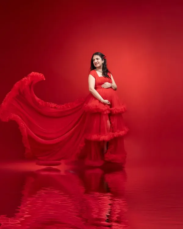 We create art that celebrates your journey to motherhood. This studio maternity portrait uses dramatic lighting and a flowing red gown to create a powerful and elegant image. The expectant mother's joyful, radiant expression is the heart of the photograph, reflecting the beauty of this chapter in her life.