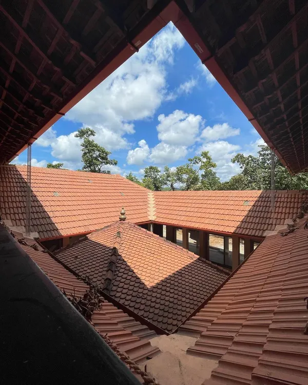 Looking up from the courtyard of 'SHANTHA-KAMALA', the Mangalore tiled roofs frame the sky, a signature element of vernacular design in the region.