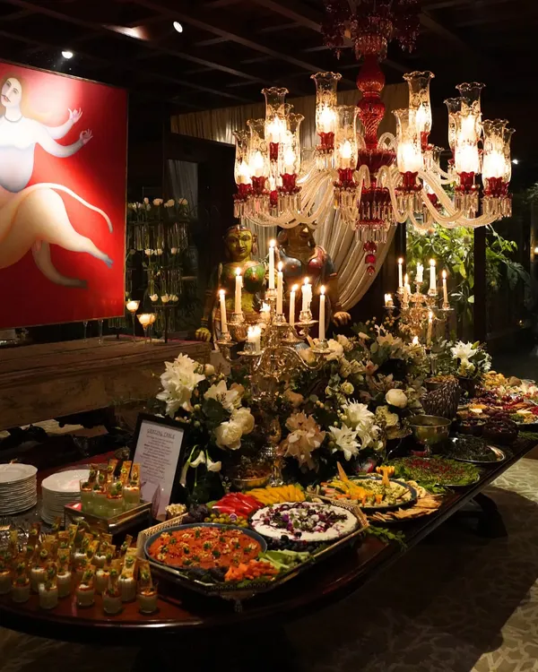 An opulent grazing table set for a grand celebration, featuring a lavish spread of international cheeses, fresh fruits, artisanal breads, and gourmet appetizers. The setup is accented with dramatic candelabras and floral arrangements, creating a truly luxurious focal point.
