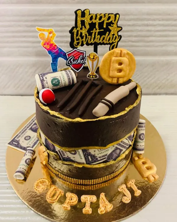 When cricket and Bitcoin are life! This unique two-tiered chocolate cake combines two passions, featuring edible money, a Bitcoin symbol, and cricket-themed fondant toppers.