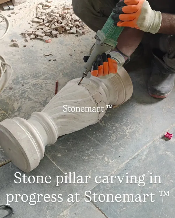 An artisan uses a precision tool for detailed carving work on a stone pillar. This piece is part of a stone birdbath fountain currently in production at our workshop.
