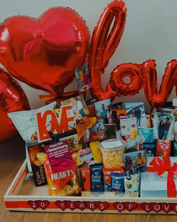 Celebrating a decade of love with this extravagant 10th-anniversary hamper. It's overflowing with snacks, chocolates, a special gift box, and large 'LOVE' balloons, all personalized with photos from the past ten years.