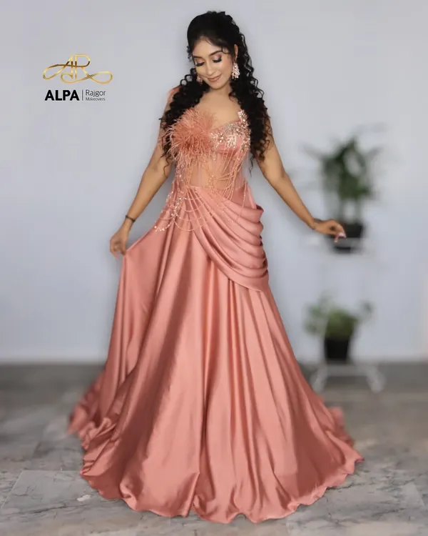 A full-length shot of a stunning peach gown perfect for a cocktail event. The makeup is glamorous with defined eyes, and the curly hairstyle adds a touch of drama.