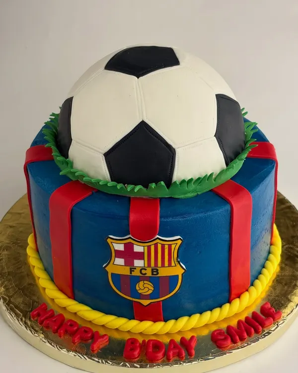 A bold FC Barcelona themed cake to celebrate a football fan's birthday. This design features the club's crest and colors, topped with a realistic football piñata.