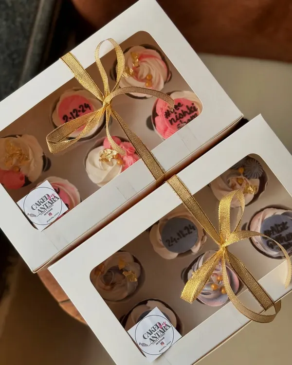 Two beautiful boxes of cupcakes I made for a bridal shower. Each cupcake is uniquely decorated with pink and grey frosting, gold leaf, and personalized toppers with the wedding date.
