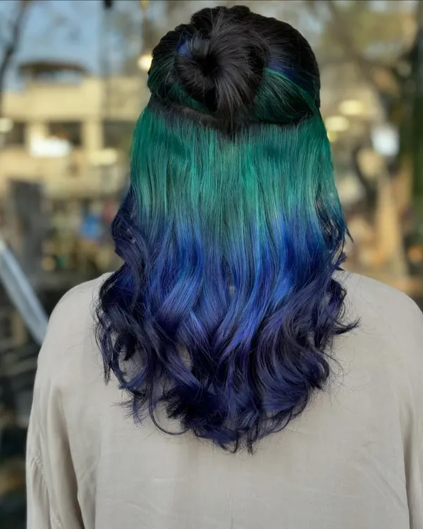 This is what we mean by a hair glow-up. We created this stunning peekaboo look with a vibrant blend of green and blue, giving the hair a hidden dimension that reveals itself with movement. This technique is perfect for expressing your personality while maintaining a professional look.