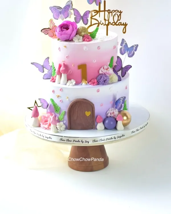 This two-tier fairy house cake is one of my favourites, perfect for a magical first birthday. I created a soft pink and purple buttercream gradient and decorated it with delicate butterflies, tiny mushrooms, and a charming little door to bring the fairy-tale theme to life.