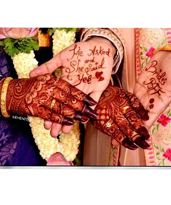 A fun and personal touch for an engagement ceremony. The groom's hand reads "He Asked and She Said Yes," while the bride's best friend has "Bride's BFF" written on her palm.