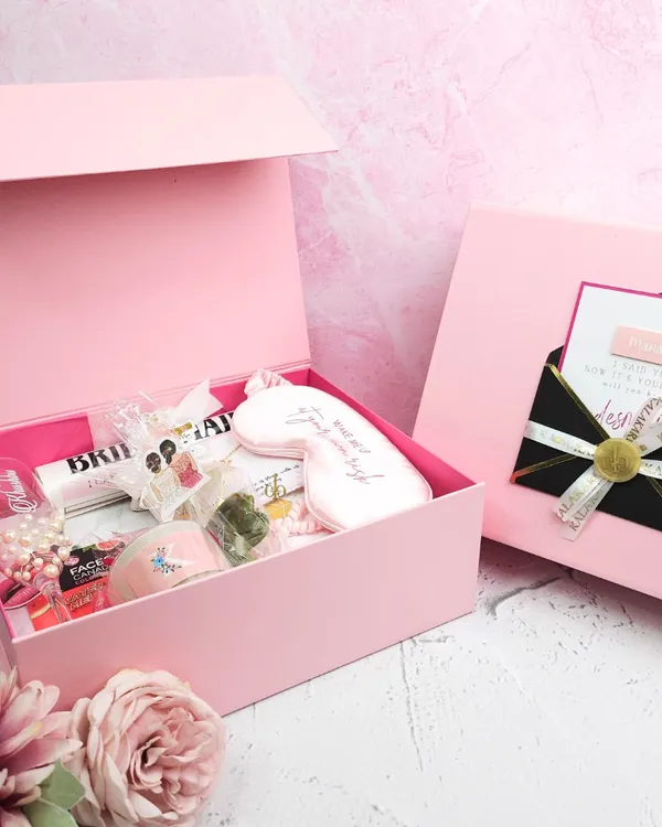 A beautifully curated bridesmaid hamper in a signature pink box. This set includes a personalized eye mask, a custom newspaper-style note, and other pampering essentials, making it the perfect way to thank your bride tribe.