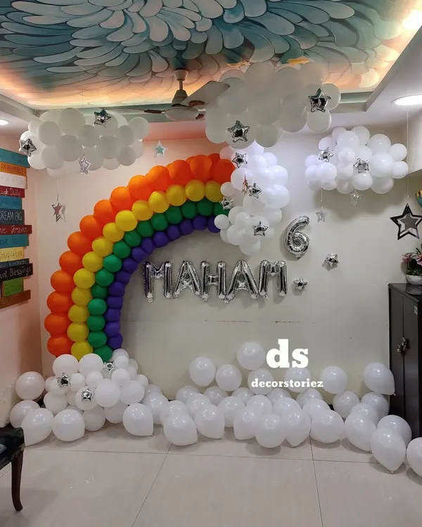 I can transform any room into a fantasy world, like this vibrant rainbow and clouds theme for a 6th birthday. This setup includes a full rainbow balloon arch, fluffy balloon clouds with star accents, and custom name and age foil balloons to create a magical sky.