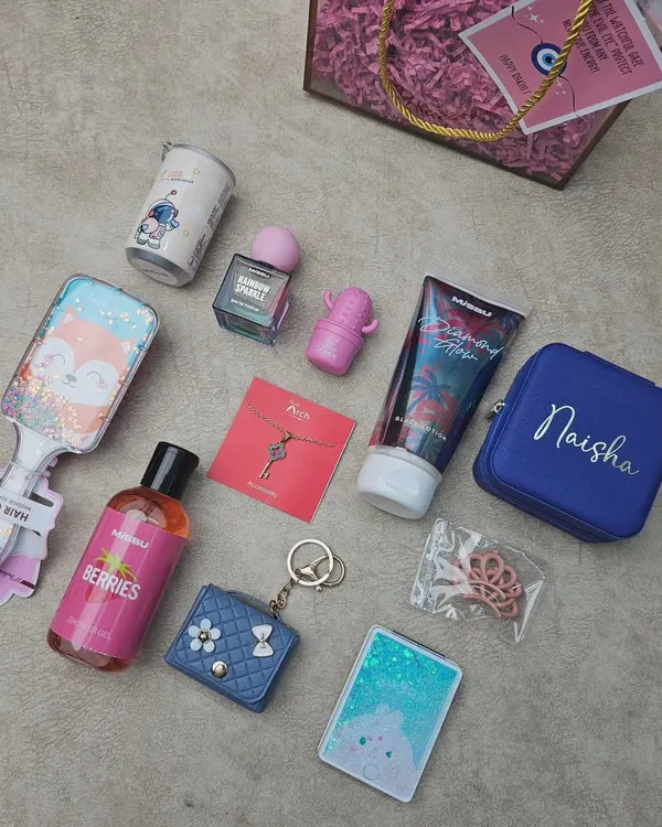 Here is a flat-lay view of the items in my 'Cute Hamper for a Sister'. It shows the personalized jewelry box, astronaut-themed mug, body lotion, perfume, hairbrush, and other fun trinkets included in the gift.