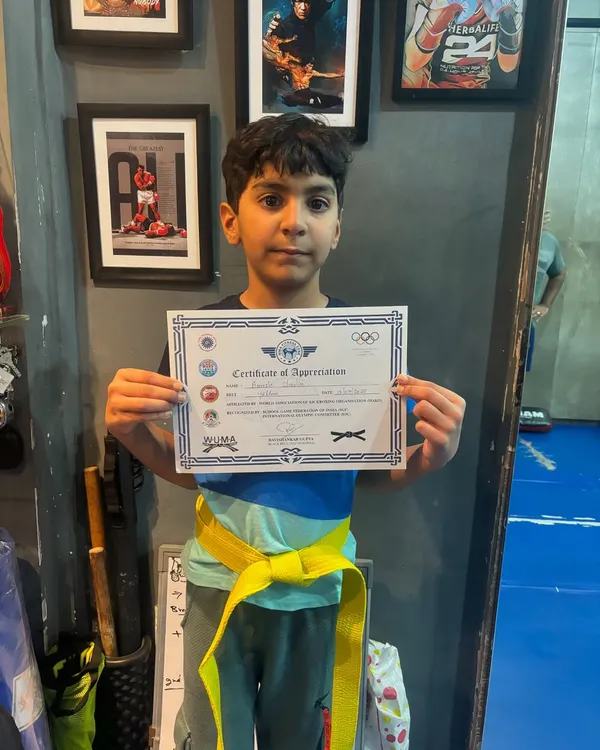 The first of many victories. This young student is proud to receive his yellow belt and certificate after passing his Level One kickboxing test.
