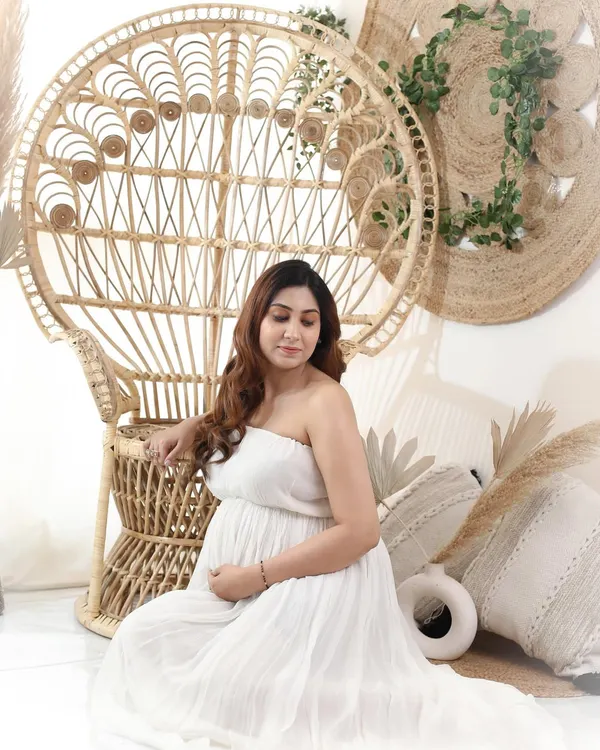 A quiet moment of reflection for this boho girl. Seated next to a peacock chair in a simple white dress, she perfectly embodies the calm and natural vibe of this style.