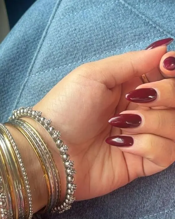 A classic and sophisticated look featuring perfectly shaped, almond gel extensions painted in a deep, glossy maroon polish.