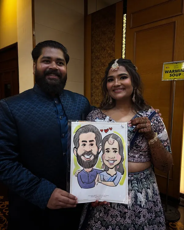 A lovely couple holding their custom portrait at what looks like a sangeet or reception. These live drawings become a memorable part of the wedding entertainment.