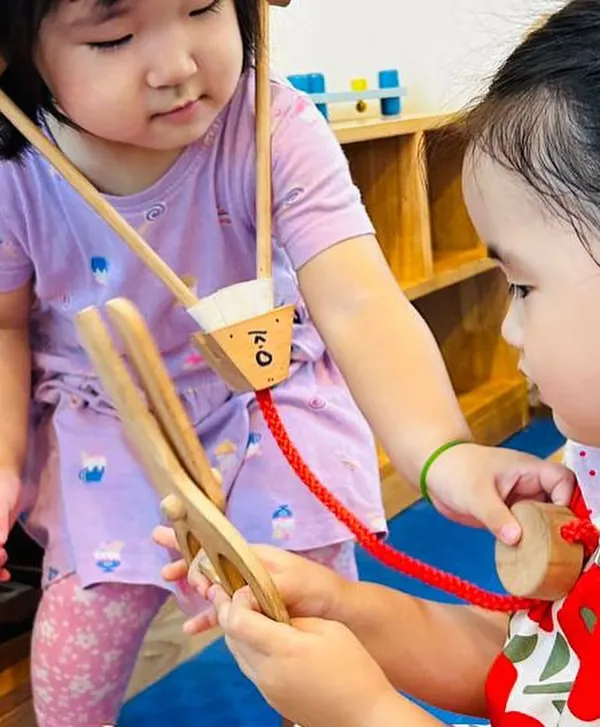 I play, I learn! Our role-play zone is a hub of activity. Here, two children are playing doctor, using a wooden stethoscope to listen to a heartbeat. This type of play helps develop empathy, communication, and an understanding of community helpers.