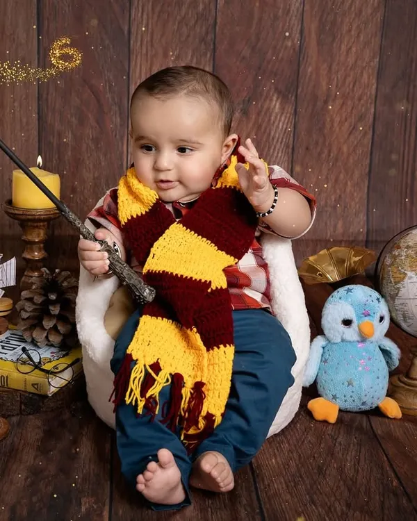Our little wizard is casting a spell of cuteness. This Harry Potter themed setup is complete with a magic wand, a Gryffindor scarf, and vintage props to create an enchanting scene for this baby's milestone session.