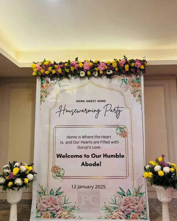 A welcoming entrance for a housewarming party. The custom "Home Sweet Home" banner, topped with a garland of fresh flowers, sets a warm and inviting tone for the new home celebration.