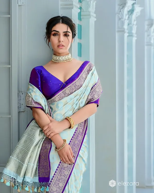 A campaign shot for saree brand Elezara. The model's elegant pose in a pastel blue and purple saree against a clean, architectural backdrop creates a look of modern sophistication.