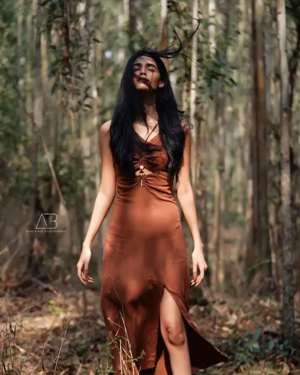 A moment of pure connection with nature. The wind in her hair and the sunlight filtering through the trees create a wild and free-spirited portrait.