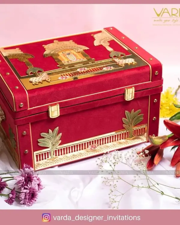 This opulent red velvet trunk is a statement piece for a grand wedding. Adorned with golden motifs inspired by traditional Indian architecture, it is designed to be a magnificent keepsake box long after the celebration.