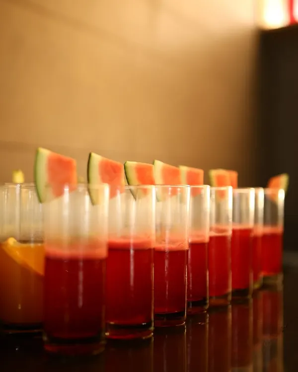 A refreshing start or a sweet interlude. These glasses of fresh watermelon juice, neatly lined up and garnished with fruit slices, are a simple yet elegant beverage option for any event.