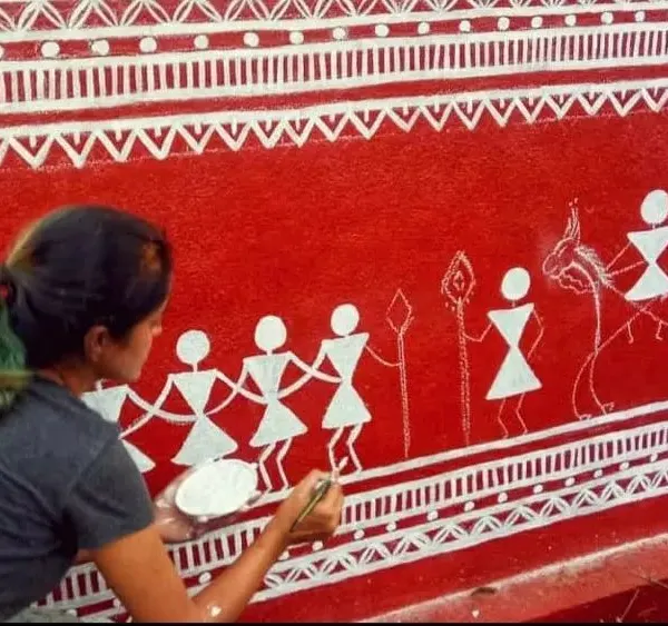 I love working with traditional art forms. Here I am painting a Warli mural, using its simple, geometric language to tell a story of community and celebration.