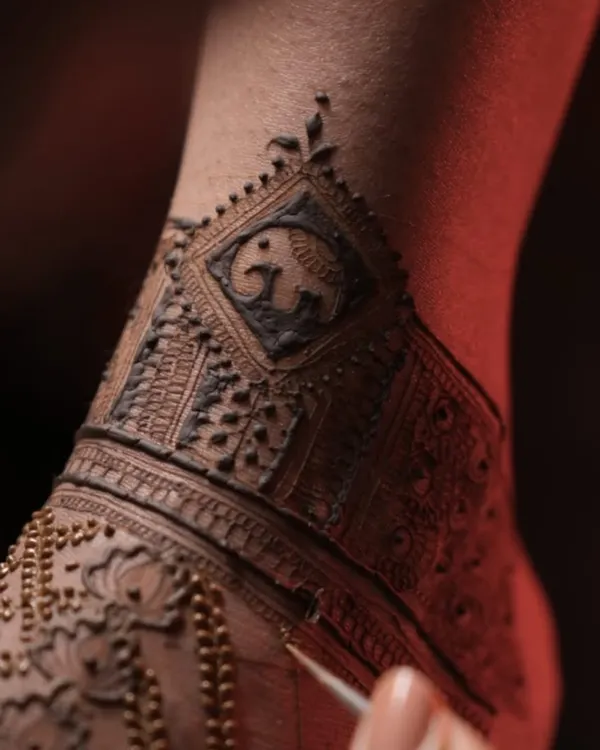 A close-up of a bridal foot mehendi in progress. This design features a small, cute elephant motif within a geometric band, a symbol of strength and good luck.