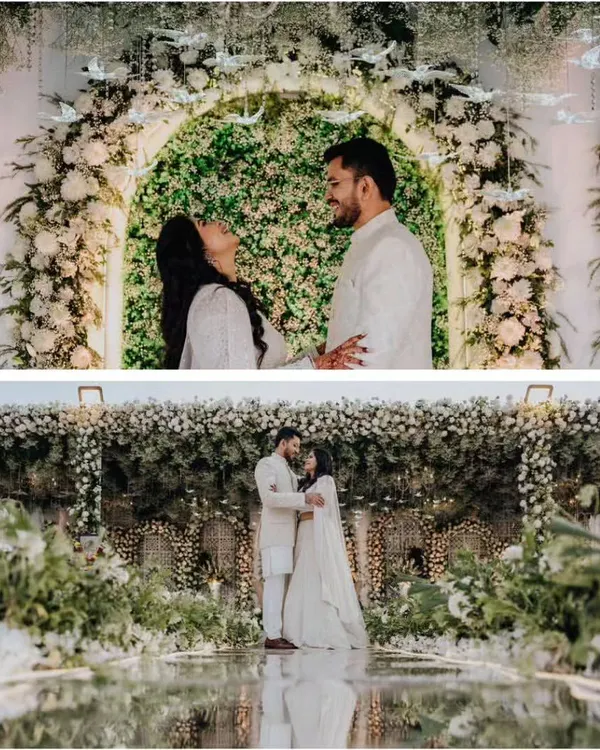 A beautiful couple portrait from an elegant green and white themed engagement. The backdrop is a stunning arch of white flowers and greenery, with whimsical glass birds hanging from above.