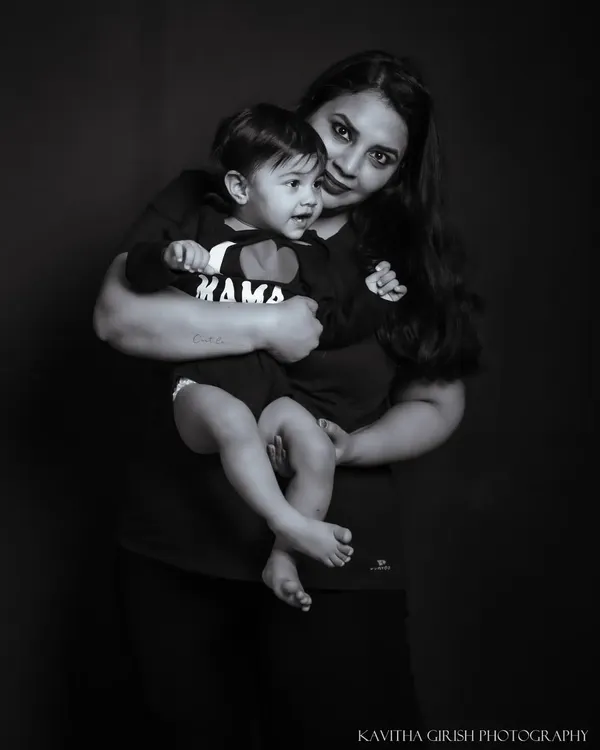 A simple and powerful black and white portrait of a mother and her child. The dark background and classic lighting create a timeless image focused on their embrace.