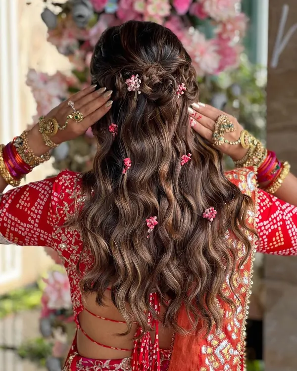 One of my favorite styles to create. This half-up look features a braided crown and soft waves, with delicate pink flowers tucked in for a romantic, bohemian vibe.